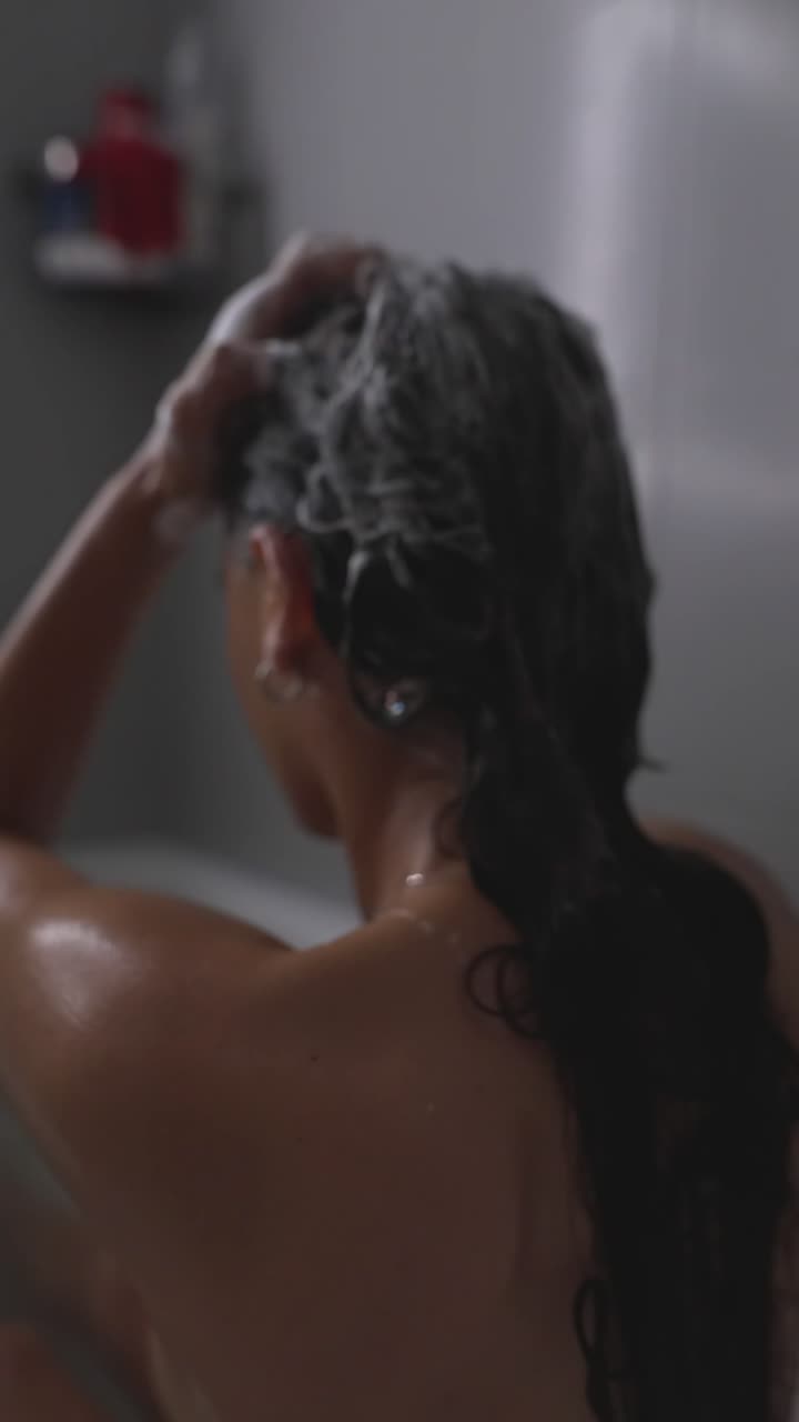 Donna che si lava i capelli sotto la doccia