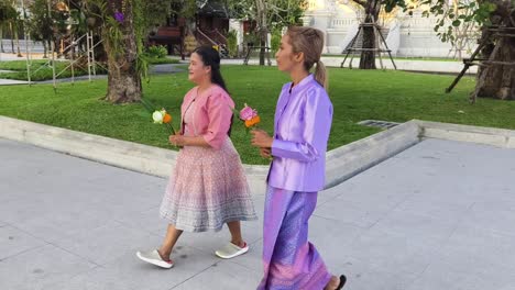 women in traditional thai dress at a temple