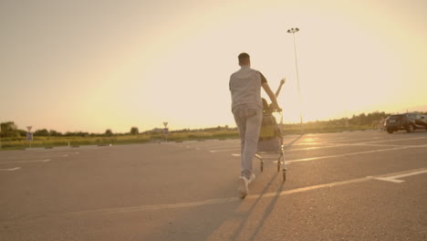 Lens-flare:-Cheerful-people-couple-man-and-woman-at-sunset-ride-supermarket-trolleys-in-slow-motion.