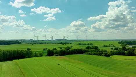 Aerial---wind-farm-with-multiple-wind-turbines-spread-across-vast-green-fields-under-a-bright-sky-with-scattered-clouds