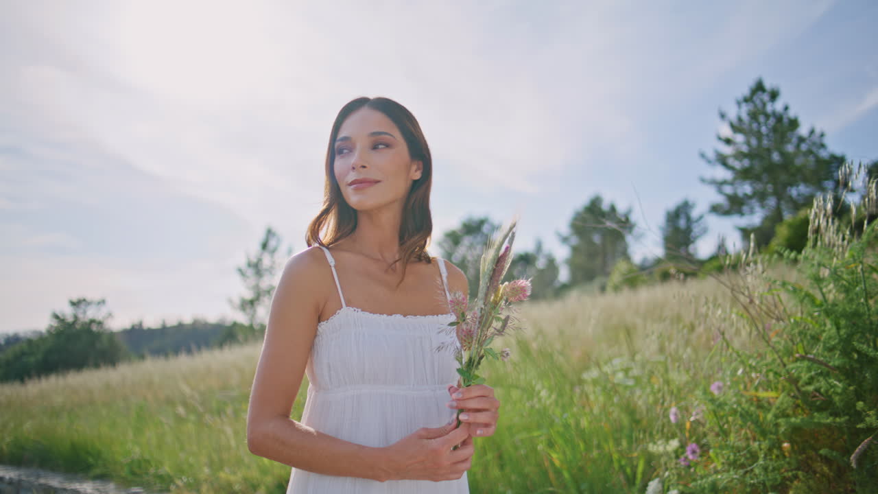 Rural model holding flowers strolling at meadow closeup. Lady carrying bouquet
