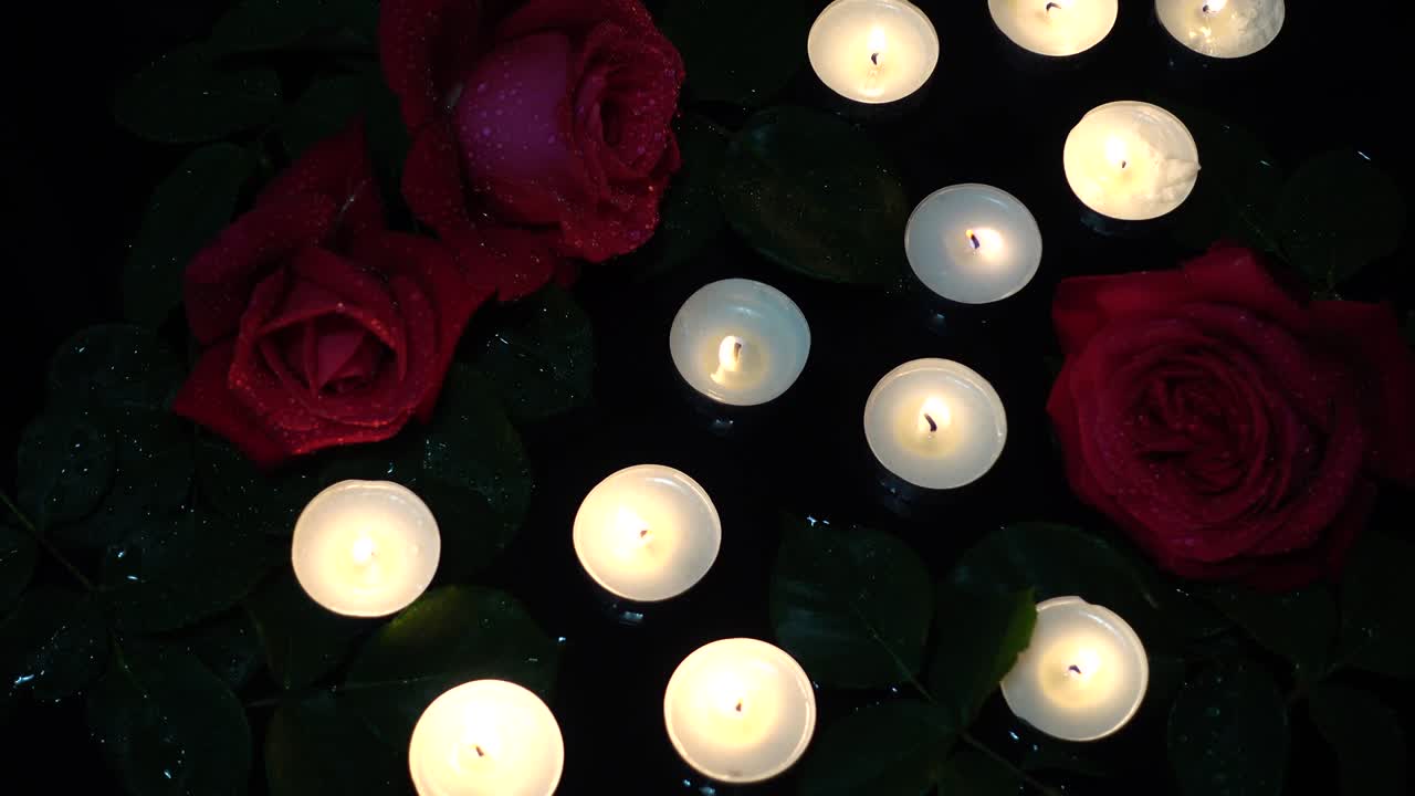 rosas y velas sobre un fondo negro.