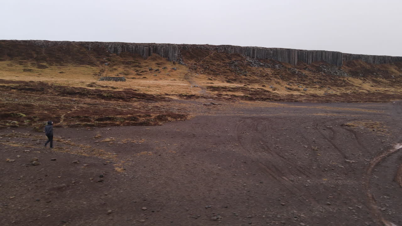 Woman walking around in front of a lava column formation in Iceland