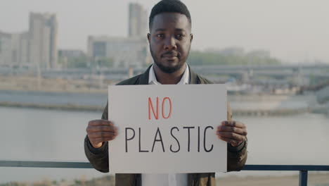 man holding "no plastic" sign