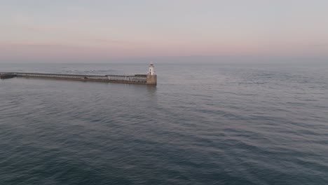 sunset drone clip of lighthouse and harbour in northumberland, england