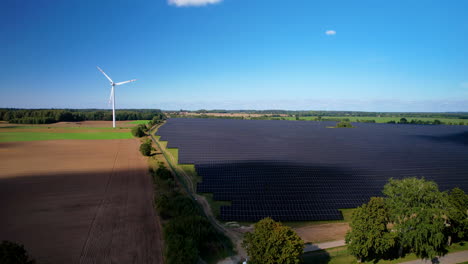 aufsteigende wolkenschatten aus der luft, die über solarzellen und windkraftanlagen auf landwirtschaftlichen flächen ziehen