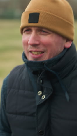 close-up of a coach jogging on a track in a stadium, talking to himself, the blurred background shows a football field