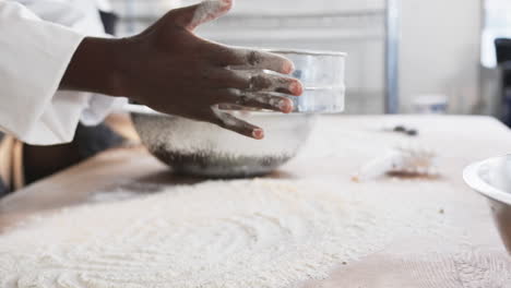 diverse bakers working in bakery kitchen, pouring flour on counter in slow motion