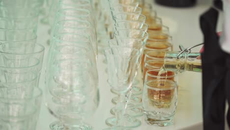el camarero vierte alcohol en vasos en la mesa blanca