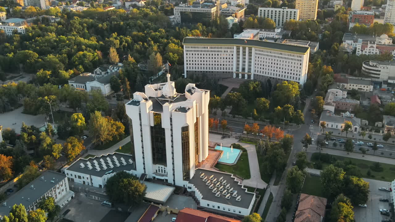 Aerial drone view of Chisinau downtown at sunset. View of Parliament, Presidency, road with moving cars and lush trees. Moldova