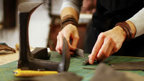 mid-section of craftswoman nailing leather