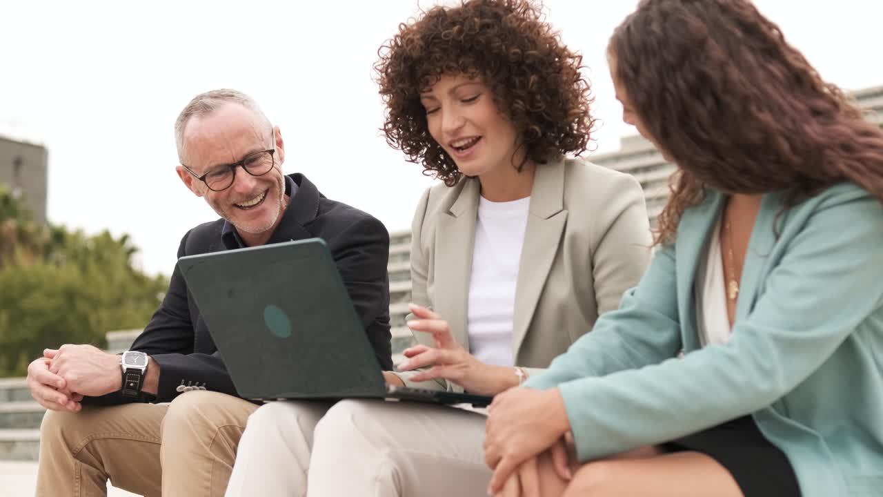 Happy businesspeople using netbook sitting on steps