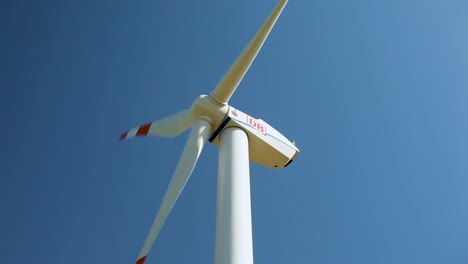a close-up view of a wind turbine generating power against a clear blue sky