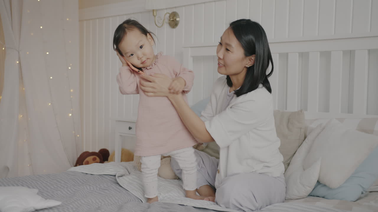 어머니와 딸이 침대에서 놀고 있다