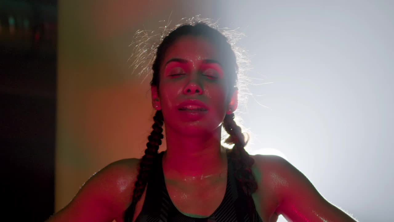 boxeadora agotada con coletas trenzadas de pie en la red, respirando pesadamente y descansando después de un entrenamiento extenuante