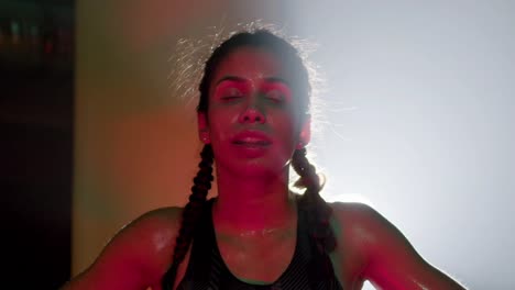 exhausted female boxer with braided pigtails standing at net, breathing heavily and having break after strenuous training