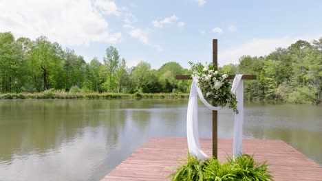 religious cross with clothe draped across blowing in the wind on the dock of a lake