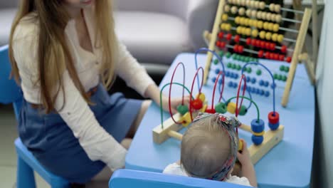 child plays with a multi-colored toy 7 mom helps