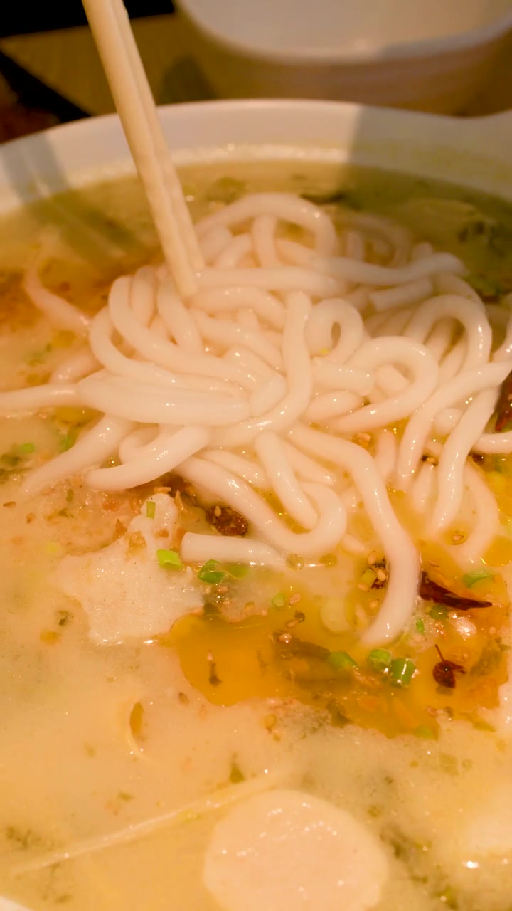 Primo piano di spaghetti di riso aggiunti a brodo piccante con polpette di pesce e peperoncini