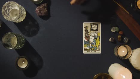 overhead shot of person giving tarot card reading laying down the death card on table