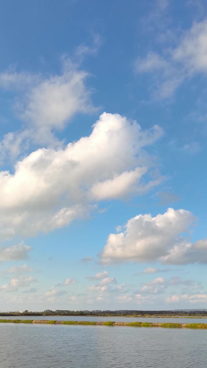 Nuvole bianche che fluttuano su un lago calmo sotto un cielo blu
