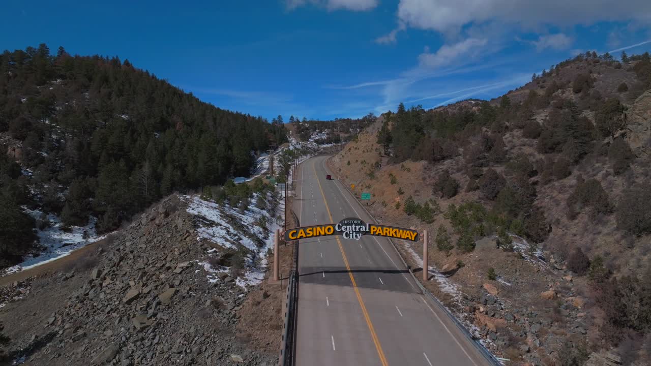 Winter Central City Parkway highway road bridge Idaho Springs Blackhawk Colorado aerial drone welcome sign snow blue sky sunny clouds forest power lines Clear Creek Gilpin County truck circle right