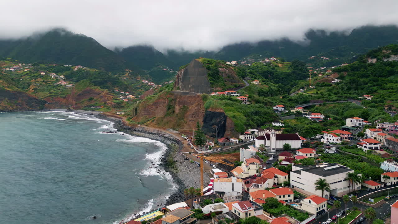 Vista aerea di un accogliente villaggio mediterraneo che si estende su verdi pendii bagnati dall'oceano