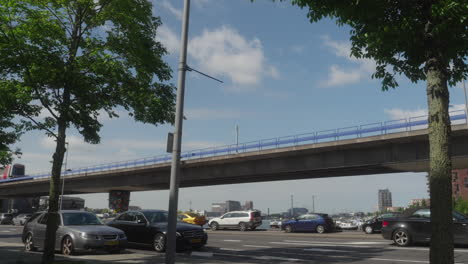 a grey metro train runs above ground through a busy street in the centre of rotterdam.