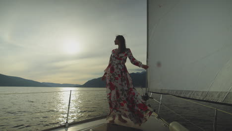 woman in a floral dress on a sailboat at sunset