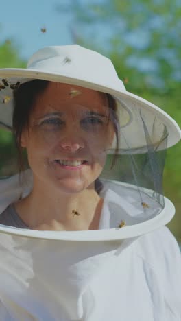 close-up of a woman beekeeper in a protective suit with bees flying around