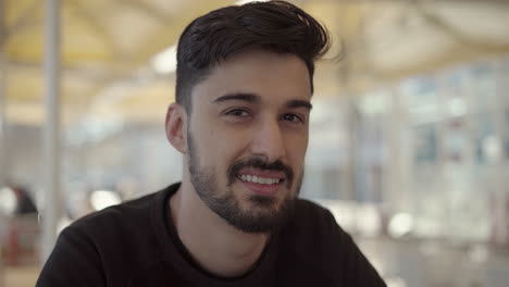 joven feliz mirando a la cámara en una cafetería