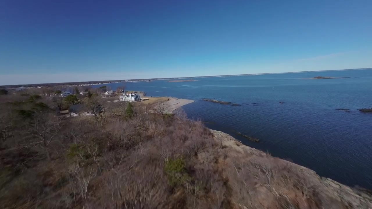 Ripresa FPV da drone che sfreccia lungo la costa frastagliata del New Hampshire, USA, volando appena sopra l'acqua e sopra le rocce che costeggiano la riva.