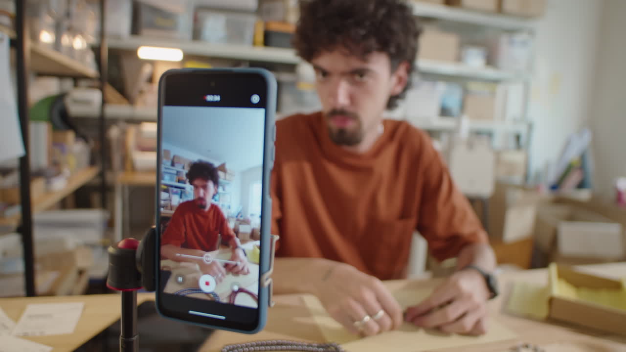 Man Filming DIY Jewelry Vlog with Smartphone