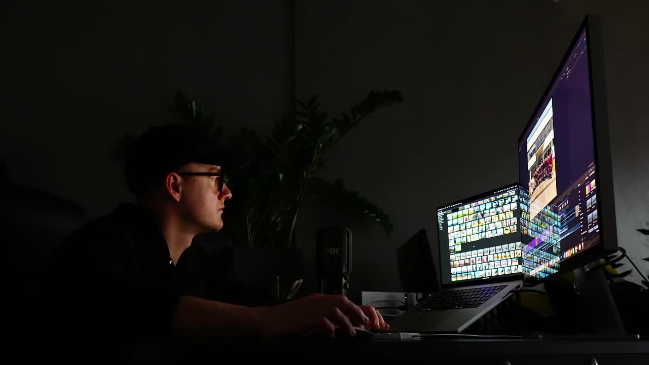 Focused Individual Expertly Navigating Multiple Monitors While Editing Digital Content in a Dark Creative Workspace