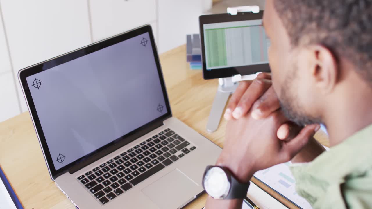 hombre afroamericano sentado en la mesa en la cocina, usando una computadora portátil con copyspace.