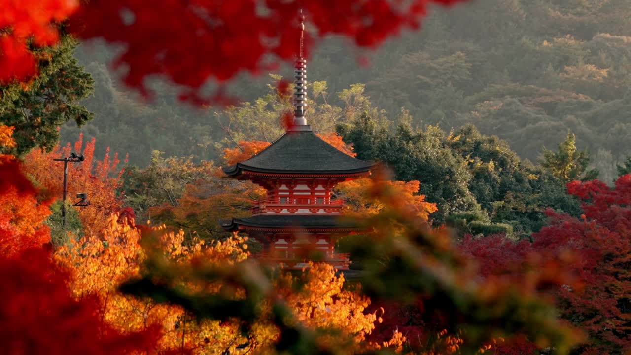 The iconic pagoda of Kiyomizu-dera Temple in Kyoto, Japan, stands majestically against a golden sunset, surrounded by vibrant red and yellow autumn foliage.