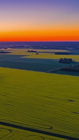 agriculture fields of latvia coutryside with orange sunset or sunrise sky, aerial vertical time lapse