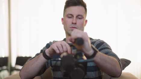 man adjusting video camera setup with focus on handheld equipment, preparing for filming. modern home studio with green walls and natural light in background, setting up for content creation