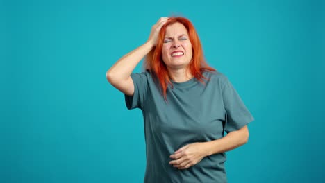 woman suffering from severe stomach ache and headache against a blue background