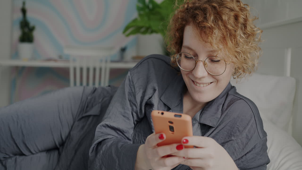 mujer relajándose en la cama y usando el teléfono