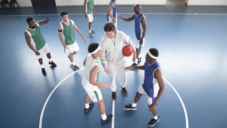 basketball players preparing for tip-off on indoor court, coach supervising game