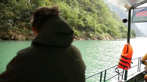 handheld shot of man on a boat staring over stream in rainforest nature site in vietnam