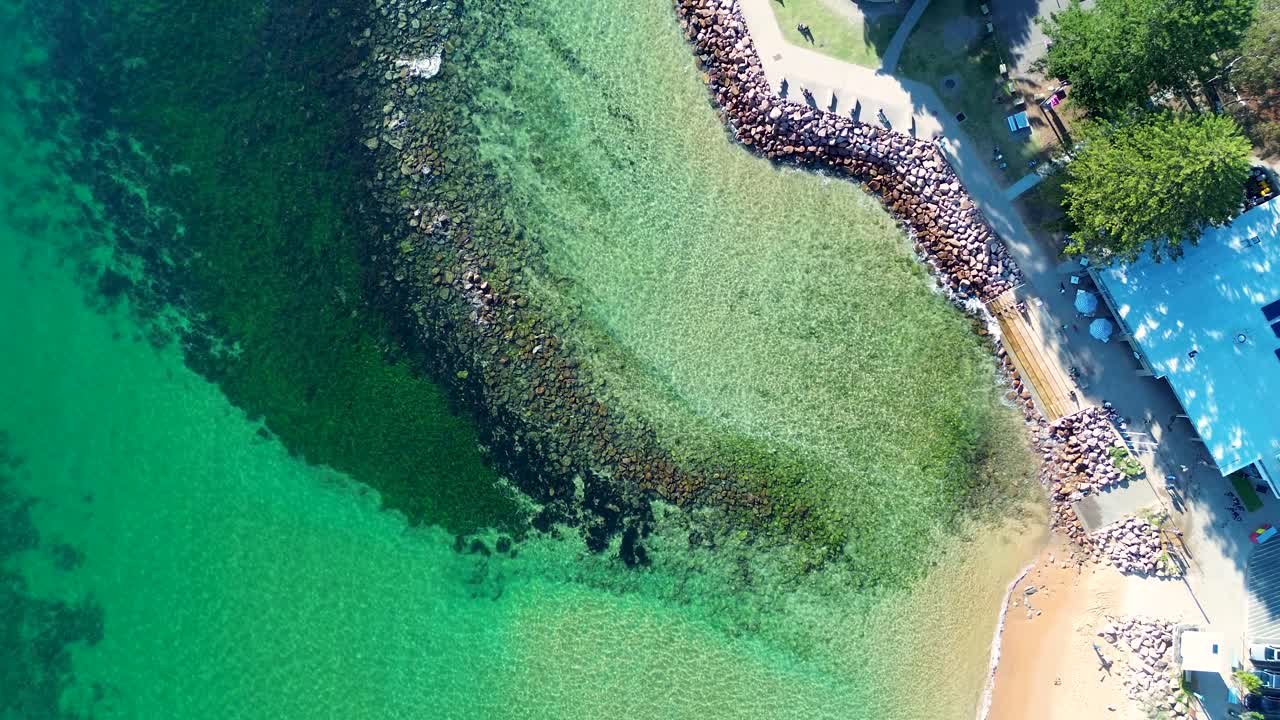 Drone aerial landscape of calm clear ocean water at Avoca Beach rocky reef pool with local café and public pathway along the scenic waterfront on the Central Coast Australia travel nature holidays