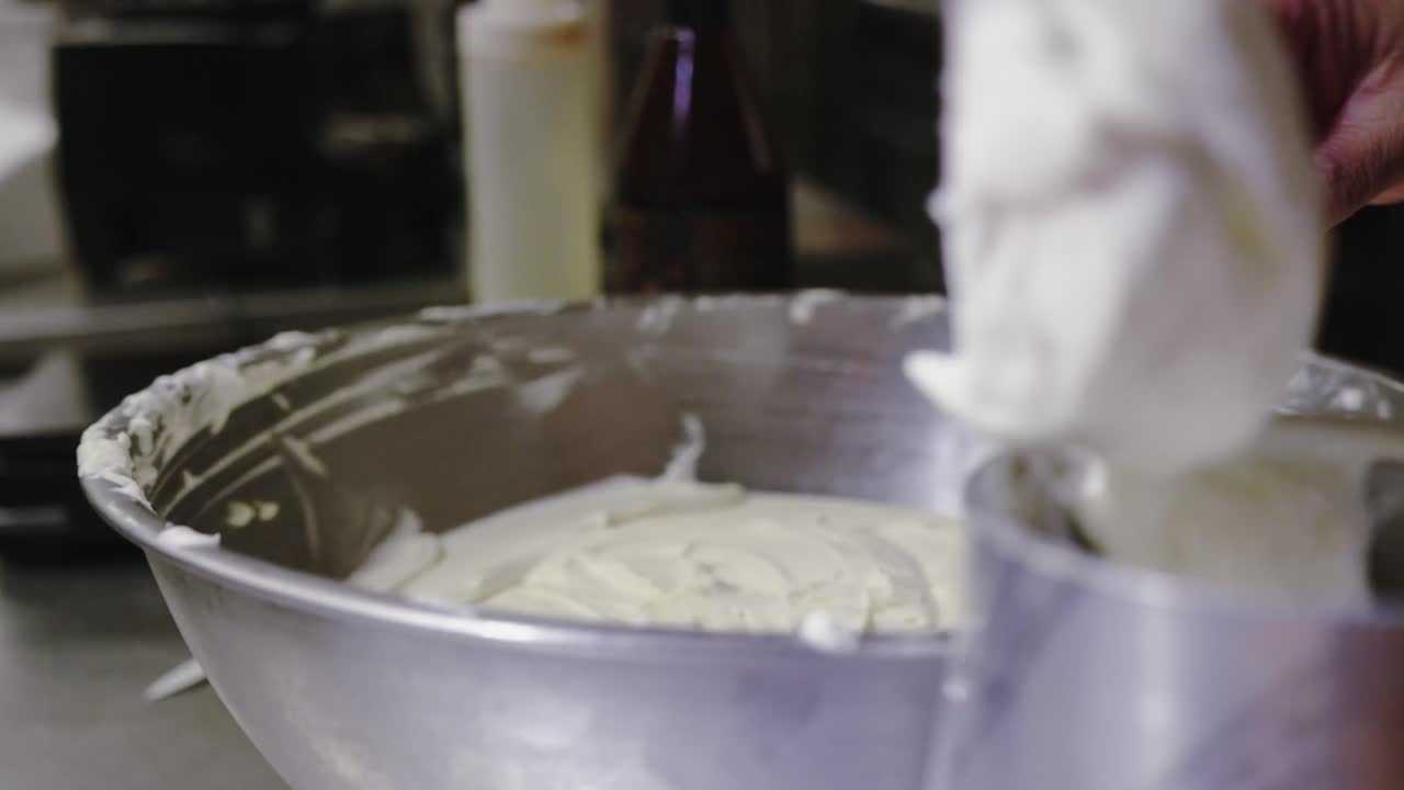 Chef putting frosting in bowl