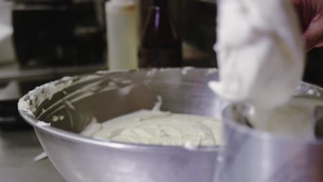 chef putting frosting in bowl