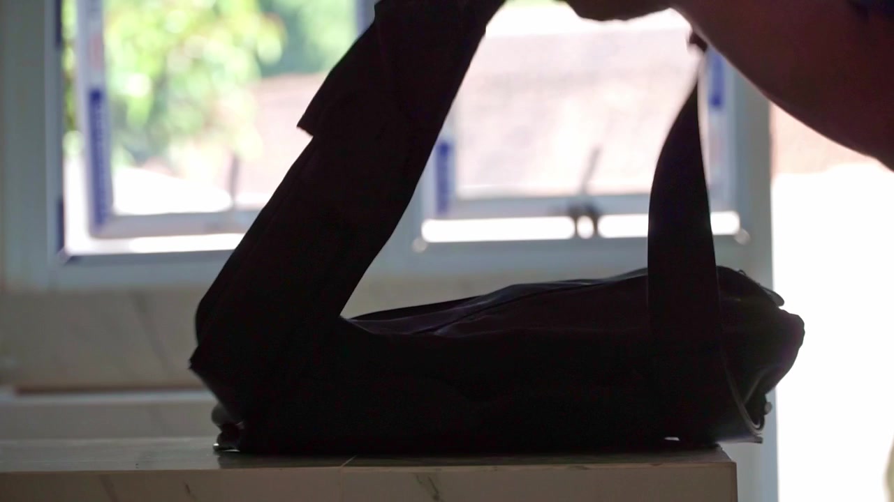 Man taking a backpack from a tabletop in a bright room. Daily commute, packing, readiness, and transportation concept.