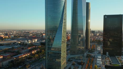 slide and pan shot of modern glossy glass office towers in cuatro torres business area. revealing long straight wide boulevard with traffic