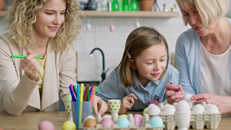 tilt up video of three generations of women painting eggs