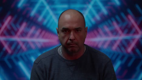 middle aged white male looking up to camera with a menacing look with a moving colorful blue background