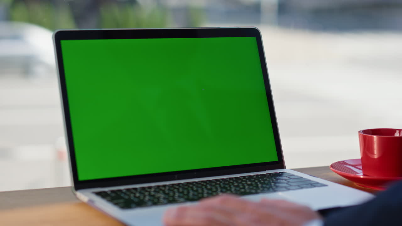 Primo piano di un manager sconosciuto che guarda un mockup di PC portatile alle finestre panoramiche della caffetteria